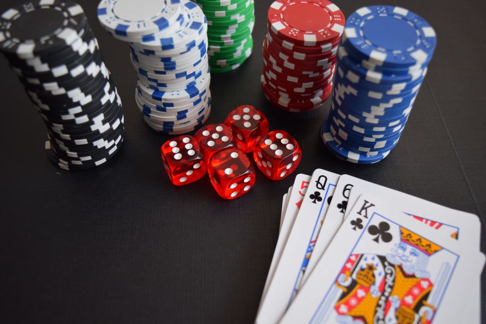 Susunan chip kasino, dadu, dan kartu remi di atas meja